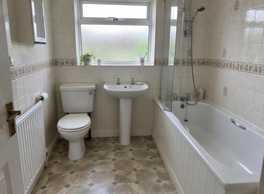 Bathroom with dated border tiles and patterned lino floor before renovation