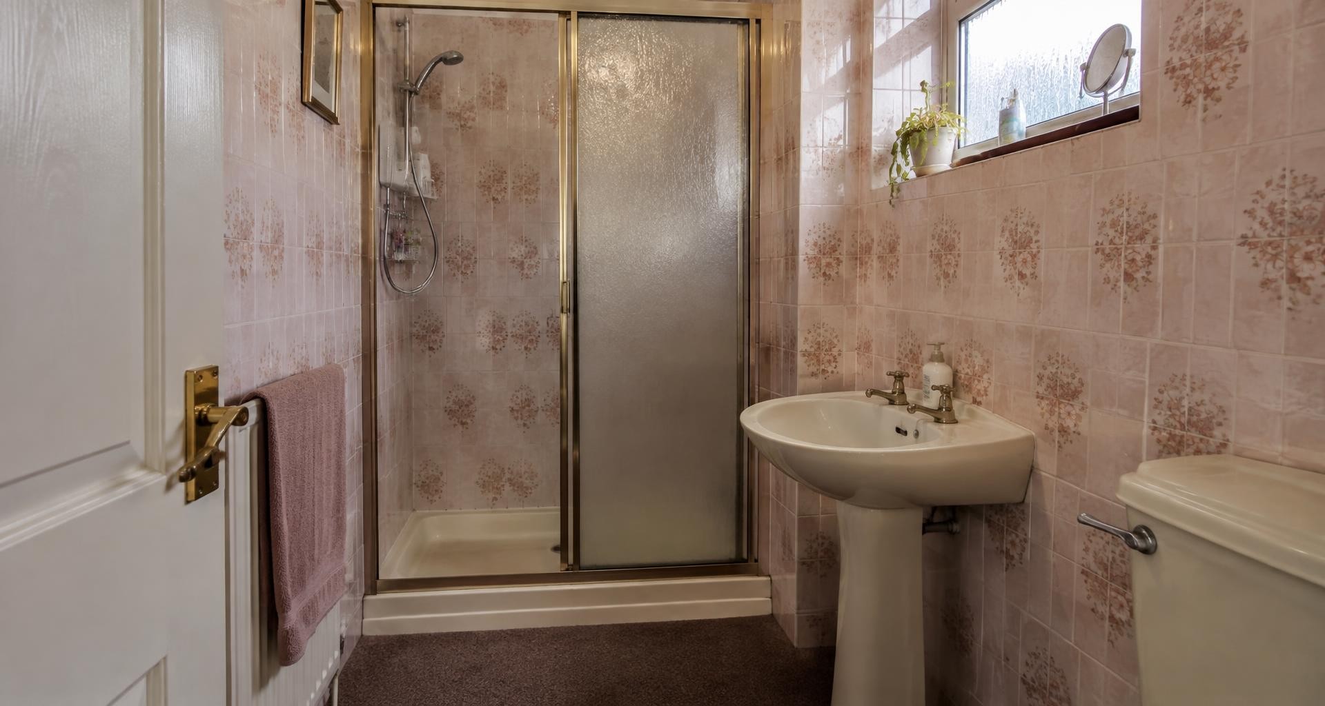 Bathroom with old pink tiles and gold shower before renovation